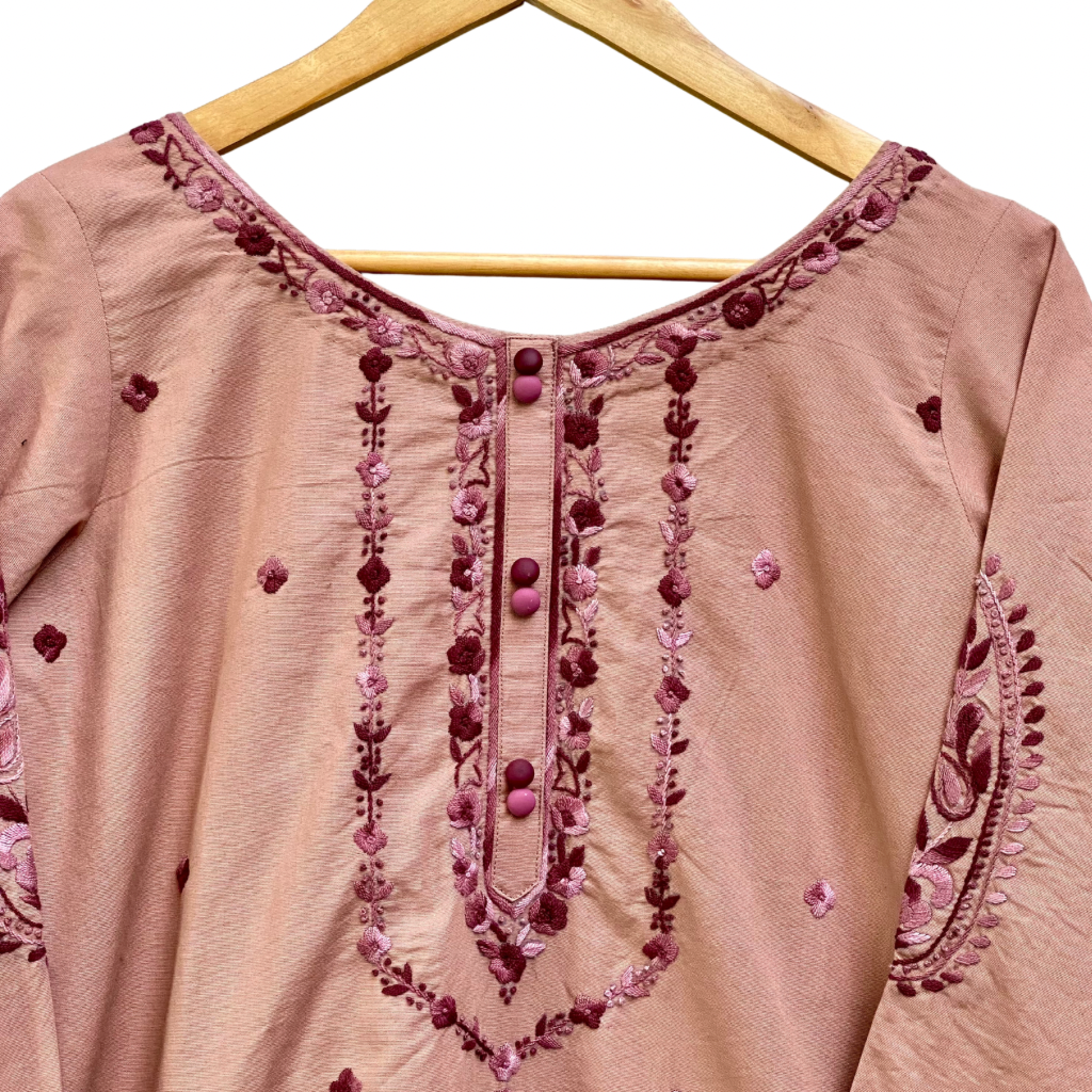 Pink embroidered garment on a wooden hanger